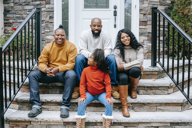 Foster family sitting on front porch steps